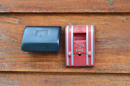 Red fire alarm on grunge wooden wallの写真素材