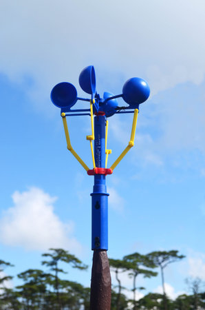 Blue anemometer in camping area against blue sky and forest background