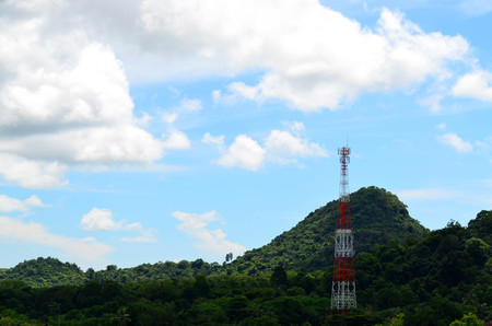 Telecommunication tower against blue sky and green mountainの写真素材