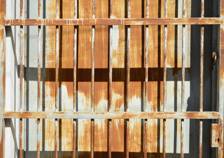 Rusty metal sheet fence with grille under sun light and shady