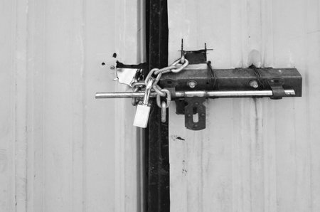Locked padlock and chained on metal sheet gate, black and white tone