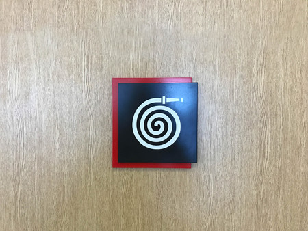 Modern fire hose sign on brown wooden wallの写真素材