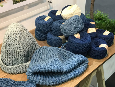 Natural color of indigo blue hand made crochet hat with pile of thread or yarn in clothes shop