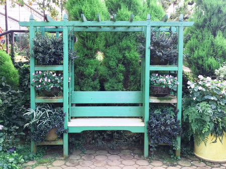 Green wooden bench among flower and pine tree