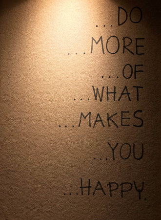 Cork board with written cheer up phrase stated do more of whate makes you happy under illuminated...