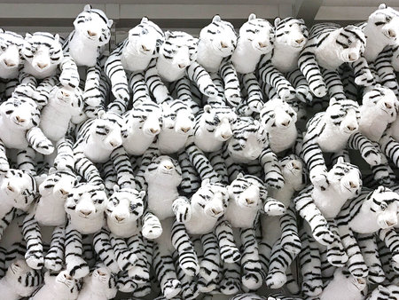 Group of white fluffy tiger  dolls are hanging on wall in toy shop