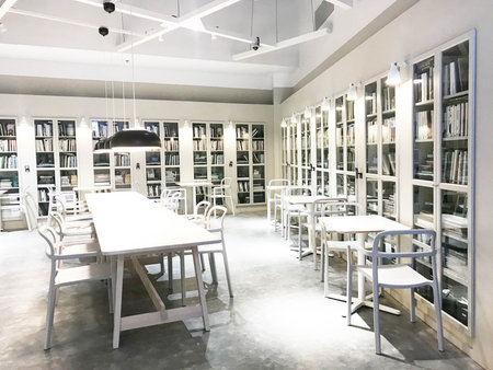 White modern bookshelf corner with tables, chairs and hanging lamp