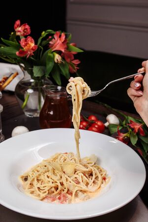 Appetizing carbonara paste with chicken improperly wound on fork. Spaghetti inaccurately hanging and falling from fork. Close up.の写真素材