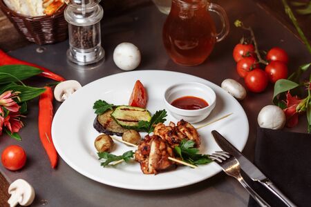 Barbecued marinated turkey or chicken meat shish kebab skewers with ketchup sauce and grilled vegetables on rustic wooden table background. Traditional barbecue grill food.の写真素材