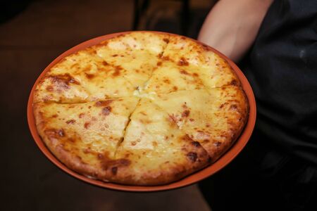 Top view on tasty traditional megrelian khachapuri - pie with melted salt cheese suluguni and egg yolk on wooden tray. Traditional georgian foodの写真素材