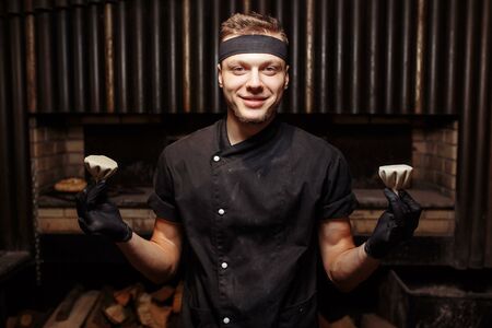 Cheerful chef posing with a serving of Khinkali. Georgian national traditional cuisine. Cooking process. Kitchen. Food conceptの写真素材
