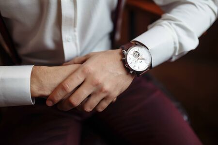 Mens wrist watch, the man is watching the time. Businessman clock, businessman checking time on his wristwatch. Grooms hands in a suit adjusting wristwatch, groom accessoriesの写真素材