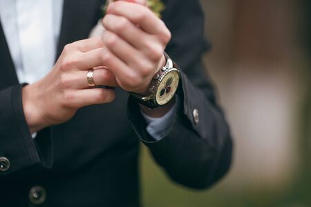 A groom putting on cuff-links as he gets dressed in formal wear. A man straightens cufflinks. Grooms suitの写真素材