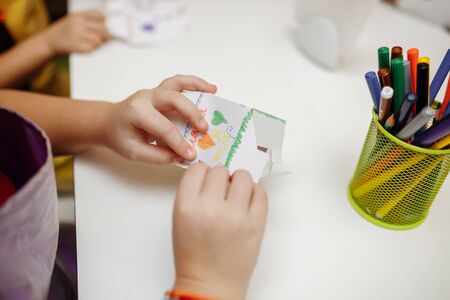 a child in training at home during quarantine makes origami out of paper. childrens creativity. hands close upの写真素材