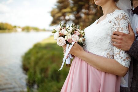 a bride in a beautiful dress with a train holding a bouquet of flowers and greeneryの写真素材