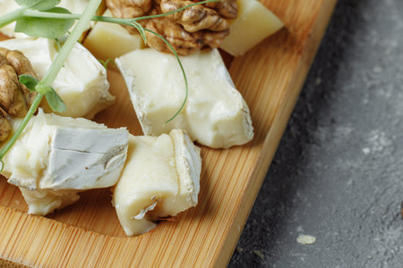 Close-up of a cheese plate. 4 types of cheese, soft white brie cheese, camembert, semi-soft briques,...