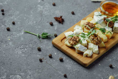 Close-up of a cheese plate. 4 types of cheese, soft white brie cheese, camembert, semi-soft briques, blue, roquefort, hard cheese. Walnuts, green grapes. Beautiful serve. restaurant.の写真素材