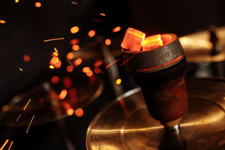 Shisha hookah with red hot coals. Sparks from breathe. Modern hookah with coconut charcoal and shisha smoke. Hookah and sparks from coals.の写真素材