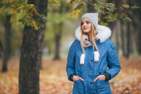 In love with nature, a girl in a jacket walks through the autumn park. warm clothes for the autumn...