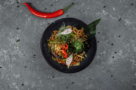 Stir-fried noodles and vegetables, in black bowl. Delicious, nutritious Asian food.の写真素材