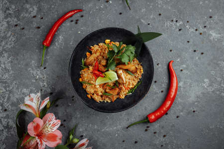 Thai rice with chicken. Thai dish of rice, chicken, Yalta onion, corn, pineapple, tomato, soy sauce, chili paste, cilantro, lime, chili pepper green onion spicesの写真素材