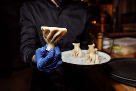 a waiter in a glove holds a khinkali in his hand.の写真素材