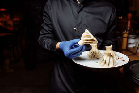 a waiter in a glove holds a khinkali in his hand.の写真素材