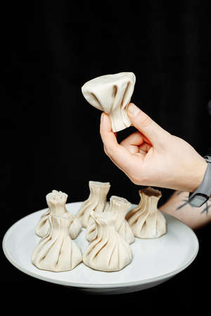 the hand holds the chikali by the tail. Khinkali in a Georgian restaurant in hand. Georgian cuisine.の写真素材