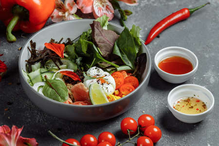 fresh healthy light breakfast, business lunch. Breakfast with poached egg, buckwheat, red fish, fresh salad, cucumbers and cherry tomatoes, business lunch concept.の写真素材