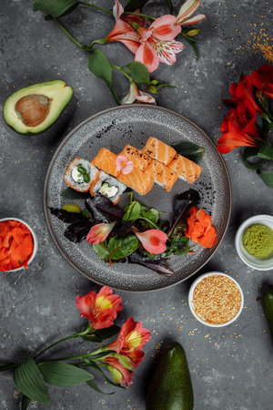 Delicious fresh sushi rolls with salmon and philadelphia cheese on gray plate on dark stone background. Traditional japanese seafood, healthy food concept.の写真素材