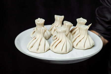 the hand holds the chikali by the tail. Khinkali in a Georgian restaurant in hand. Georgian cuisineの写真素材