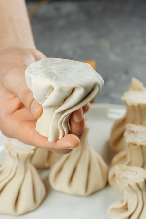 the hand holds the chikali by the tail. Khinkali in a Georgian restaurant in hand. Georgian cuisineの写真素材