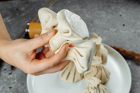 the hand holds the chikali by the tail. Khinkali in a Georgian restaurant in hand. Georgian cuisine.の写真素材