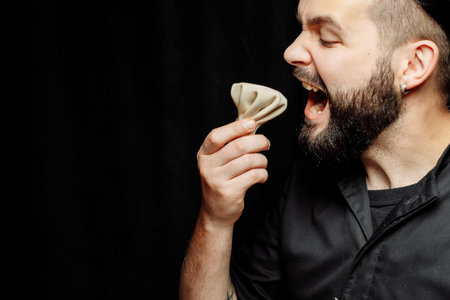 The bearded man is emotionally eating khinkali. The national Georgian dish khinkali. Concept of...