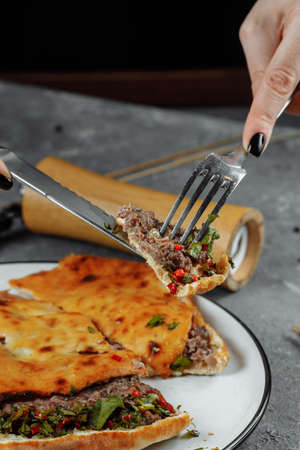 female hands with a knife and a fork cut Khachapuri with lamb and chili. Georgian national foodの写真素材