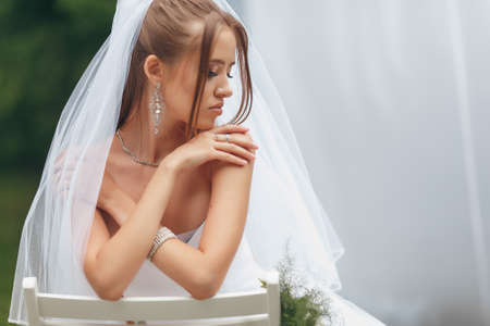 Beautiful bride in a magnificent wedding dress posing among greenery on the street. girl poses in a wedding dress for advertising. Bride concept for advertising dresses.の写真素材