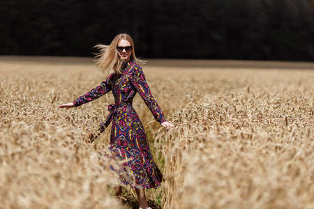 A beautiful young woman is walking in a wheat fieldの写真素材