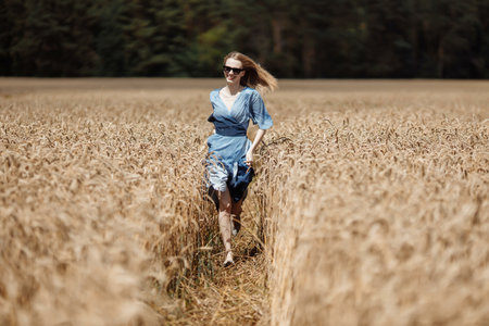 A beautiful young woman is walking in a wheat field