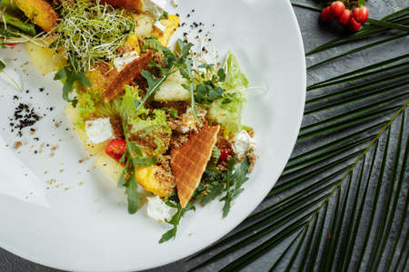 Summer diet salad with leaves of lettuce, watermelon, peach and feta cheese. On a light blue background copy spaceの写真素材