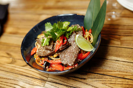 noodles with veal and vegetables on a gray table.の写真素材