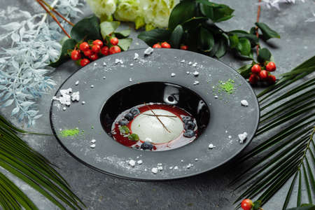 Panna cotta with raspberry sauce in a black plate.の写真素材
