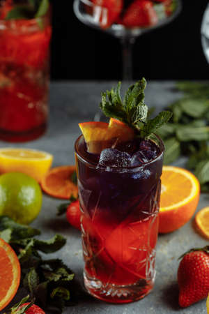 Colorful refreshing drinks for summer, cold strawberry lemonade juice with ice cubes in the glasses garnished with sliced fresh lemons.の写真素材