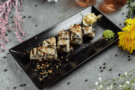 Golden dragon sushi roll with tuna, eel, cucumber, sesame seeds and tobiko caviar on wood background.の写真素材