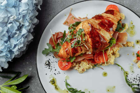Delicious croissant sandwich with ham, cheese and scrambled eggs on plate served.の写真素材