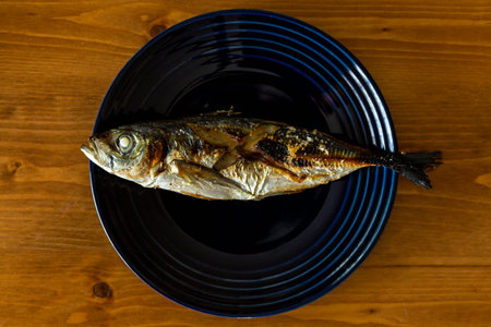 Grilled fish (Horse mackerel) on a plate on a wooden table. Top viewの写真素材