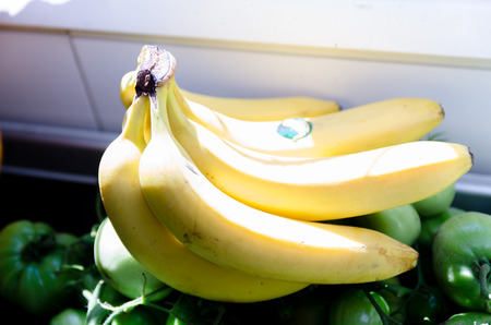 Bananas lie on immature tomatoes on the countertop in the kitchenの写真素材