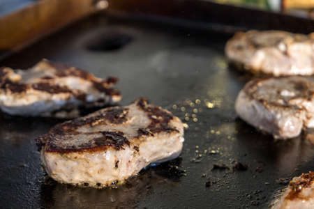 Marinated boneless pork chops cooking on a hibachi style outdoor large griddleの写真素材