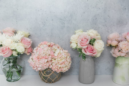 Several rose, peony and hydrangea flower arrangement bouquets against a horizontal concrete wallの写真素材