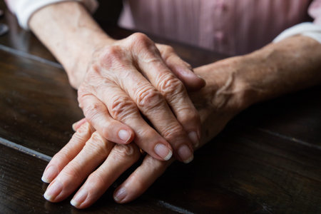 A pair of elderly woman grandmothers hands folded and laying on top of each other.