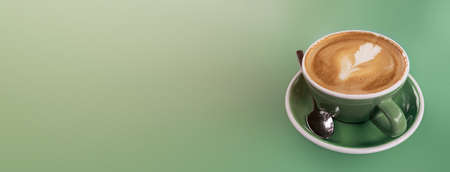 a hot vanilla latte in a green ceramic cup on a tone on tone green long backgroundの写真素材